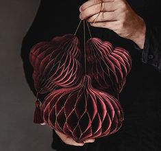 a man holding three red paper flowers in his hands, with one hanging from the string