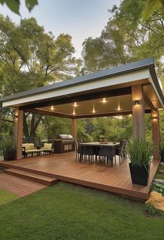 a wooden deck with a table and chairs under a covered gazebo surrounded by trees