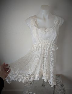 "This long top is a refashion from a 1970's sample wedding dress. The bodice is lace over sheer, lined with taffeta. The scooped neck and front are embellished with lace, pearls and sequins. The lace is continued over the shoulders and around the back V-neck. A long lace 'skirt' with added ruffle of lace complete the look. Back closure is four snaps. A vintage aurora borealis piece of jewelry with three suspended stones adds sparkle. Size S Inside measurements of garment: Bust- 34\" Bottom of crop (diameter) -28\" Back length(top of shoulder to bottom edge) - 32\" *note, please take your measurements and use them as a guide for sizing. * because this is repurposed from a vintage gown, be aware that there will be some imperfections in the    garment." Fitted Lace Dress With Lace Work, Fitted Bodice Lace Dress, Sheer Sleeveless Lace Wedding Dress, Lace Dress With Fitted Bodice And Lace Patchwork, Feminine Lace Bodice For Wedding, Delicate Lace Top For Wedding Night, Feminine Wedding Lace With Lace Bodice, Fitted Bodice Lace Dress With Delicate Lace, Feminine Sheer Lace Dress For Wedding