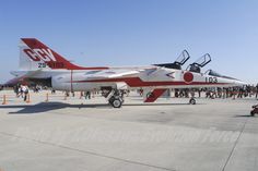 an airplane is parked on the tarmac with people around it and other planes in the background