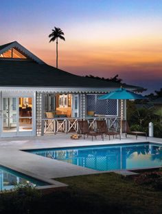 a house with a pool in front of it at night, surrounded by palm trees