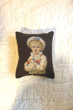 a black pillow with a woman's face on it sitting on top of a bed