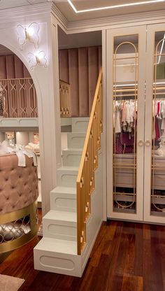 the closet is full of clothes and has stairs leading up to an upper level bed