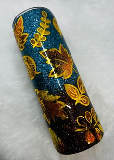 a blue, yellow and black glass vase with gold designs on it sitting on a white furnishing