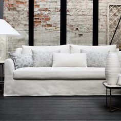 a white couch sitting on top of a hard wood floor next to a brick wall