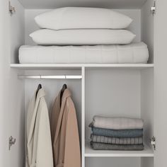 an open closet with folded clothes and pillows