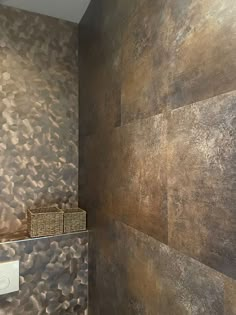 a bathroom with metallic wallpaper and a basket on the shelf in front of it