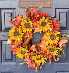 a wreath with sunflowers and autumn leaves on a blue door