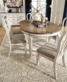 a dining room table with chairs and a rug on the floor in front of it