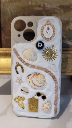 a cell phone case with shells and other items on the back cover, sitting on a table