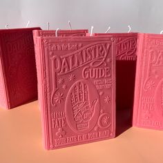 three pink book shaped candles sitting on top of a table