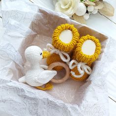 two crocheted toys in a box on a table next to flowers and candles