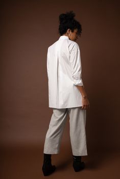 This oversized tunic is draped to be comfortable and flattering on a woman’s body. This style has a beautiful inverted pleat at the back and a unique exaggerated collar. The side slits balance the long length of this elegant and boxy number. Contents: 100% GOTS*-Certified Organic Cotton Natural shell buttons Fit: This style is made to fit oversized; please order the size you normally take. See our sizing guide here. Model is 5'9" and wears a size 6. Care: Machine wash cold. Line dry. A garment's Chic Oversized Tunic For Loungewear, Oversized Tunic With Shirttail Hem, Oversized Tunic For Layering, Oversized Lagenlook Tunic For Loungewear, Oversized Blouse With Shirttail Hem For Loungewear, Fall Relaxed Fit Tunic With Shirttail Hem, Fall Tunic With Relaxed Fit And Shirttail Hem, Oversized Lagenlook Tunic For Daywear, Chic Oversized Tunic For Work