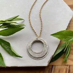 This elegant necklace offers up a unique combination of playfulness & timeless style. Ten organically shaped & uniquely textured sterling silver circles layer gracefully on a beautiful 14K gold filled double cable chain. Each ring is handcrafted individually to represent your journey through the decades. Circles are hammered flat & strong, and given a rustic sparkly texture. The circles shimmer & move gracefully with you, capturing the light & landing in various arrays. This piece is a beautiful Modern Hammered Round Necklace, Sterling Silver Necklaces For Layering, Sterling Silver Round Necklaces For Layering, Hammered Jewelry With A Modern Twist As A Gift, Hammered Modern Twist Jewelry For Gifts, Modern Twist Hammered Jewelry As Gift, Layering Sterling Silver Necklaces, Mixed Metal Necklace, Through The Decades