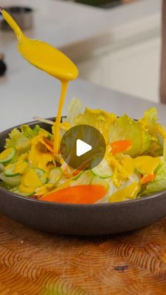 a person pouring dressing into a salad in a bowl