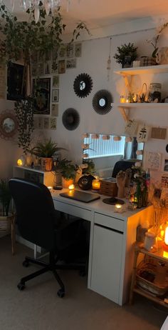 an image of a home office with candles on the desk and pictures hanging above it