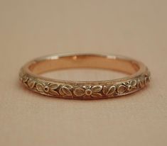 an antique wedding band with flowers and leaves engraved on the side in yellow gold or white gold