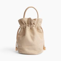 a small beige bag with a drawstring on the front and side, against a white background