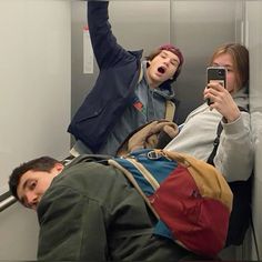 three people taking pictures on their cell phones while riding the subway train in new york city