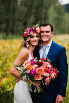 a bride and groom pose for a wedding photo in front of wildflowers at their outdoor ceremony