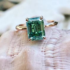 an emerald ring sitting on top of a rock