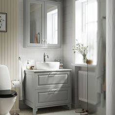 a bathroom with a sink, mirror and toilet in it's corner next to a window