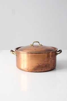 an old copper pot sitting on top of a white counter