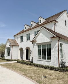 a white brick house with brown shingles on the roof