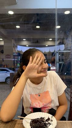 a woman sitting at a table with a piece of cake in front of her face