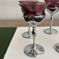 three wine glasses sitting on top of a white table next to green placemats