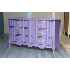 a purple dresser with gold trim and drawers on the bottom, sitting in a room