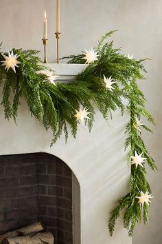 a fireplace decorated for christmas with greenery and white star garland on the mantel