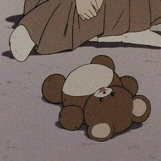 a brown teddy bear laying on the ground next to a person in a kimono