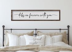 a bed with two pillows and a framed sign above it