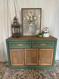 a green dresser with two drawers and a painting on the wall next to it,