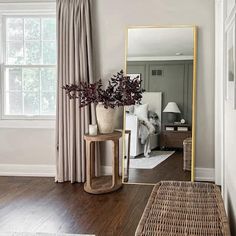 a large mirror sitting on top of a wooden floor in a living room next to a window