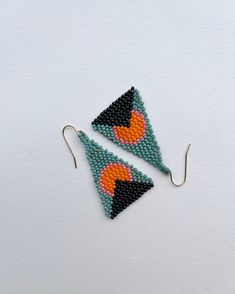 two triangle shaped beaded earrings on white background