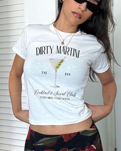 Dirty Martini Social Club Baby Tee, Martini Coquette Shirt, Extra Dirty Shirt, Vintage Tee, Y2K tee, Cocktail Tshirt, Martini Top, Tini Time *IMPORTANT PLEASE READ BEFORE PURCHASING* My store uses DTG (Direct to Garment) printing. This means the design is printed into the garment. This means it is designed to last longer than other printing processes. Due to this printing process the design colors may not be as vibrant as shown in the photos. There may at times be a slight difference between rea Fitted Short Sleeve T-shirt With Letter Print, Fitted White T-shirt With Text Print, Fitted Basic T-shirt With Funny Print, Fitted Short Sleeve Top With Screen Print, Fitted Short Sleeve Graphic Tee Shirt, Fitted Crew Neck Shirt With Screen Print, Fitted Basic Tops With Screen Print, Fitted Short Sleeve Tops With Text Print, Fitted Basic Top With Screen Print