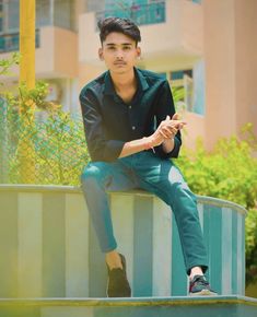 a young man sitting on top of a metal rail next to a tall white building