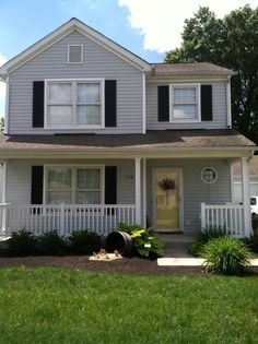 a white house with black shutters on the front and side windows, grass in front