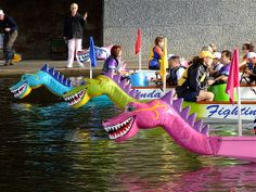 there are many people riding boats in the water with dragon heads on it's sides