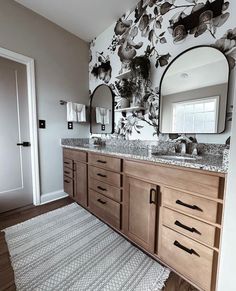 a bathroom with two sinks, mirrors and rugs on the floor in front of it