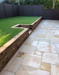 an outdoor area with grass and wooden planters on the side, surrounded by fenced in