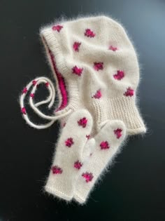 a knitted mitten and glove sitting on top of a black table next to each other