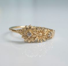 This dainty daisy ring is a beautiful little stacking ring that is like a little bouquet of gold flowers and diamonds wrapped around your fingers. This ring is made in solid 14 karat gold with and set with two genuine VS-SI white diamonds. Gentle Daisies embody many meanings, from joy to good luck and new beginnings. In Victorian times, they were taken to represent loyalty and trust. Innocent daisies are a simple flower with many meanings, and are a perfect daily ring companion, sure to make you Gold Daisy Ring, Delicate Flower Shaped Stackable Rings For Promise, Delicate Flower Shaped Stackable Promise Rings, Delicate Flower Ring With Rose Cut Diamonds, Dainty Yellow Gold Cluster Ring, Dainty Flower Ring With Rose Cut Diamonds As Gift, Dainty Flower Promise Ring, Delicate 14k Gold Stackable Flower Ring, Delicate Stackable Rings With Rose Cut Diamonds