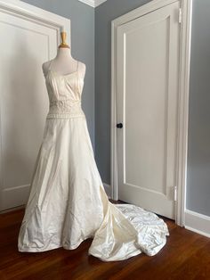 a white wedding dress is on display in the corner of a room with blue walls