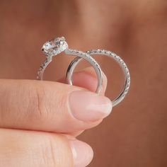 a close up of a person holding two wedding rings with diamonds on each one side