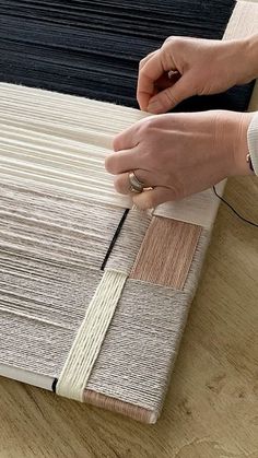 a person is working on an area rug with different colors and patterns, including black, white, beige, and grey