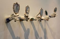 five white hands holding mirrors on the wall