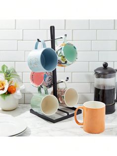 coffee mugs and teapots on a marble counter top with white tiles in the background